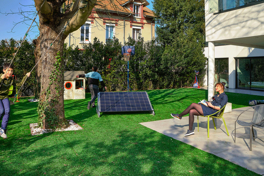 kit solaire dans un jardin autour d'une personne qui lit et d'enfants qui jouent